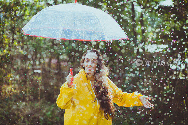 秋雨中带着透明塑料伞的快乐女人