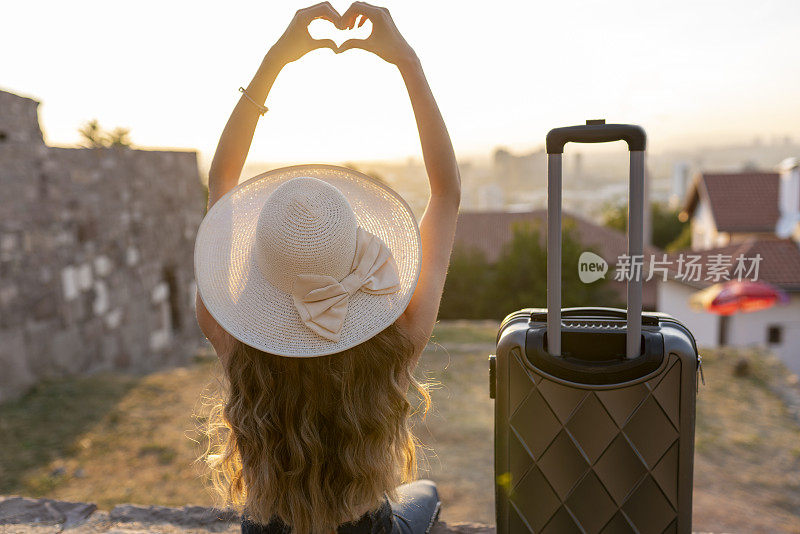 年轻的金发女人提着箱子在街上旅行