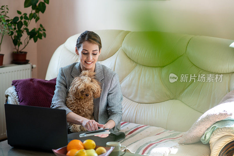 一个年轻女子坐在客厅里，她的狗坐在她的腿上，看着她的议程。