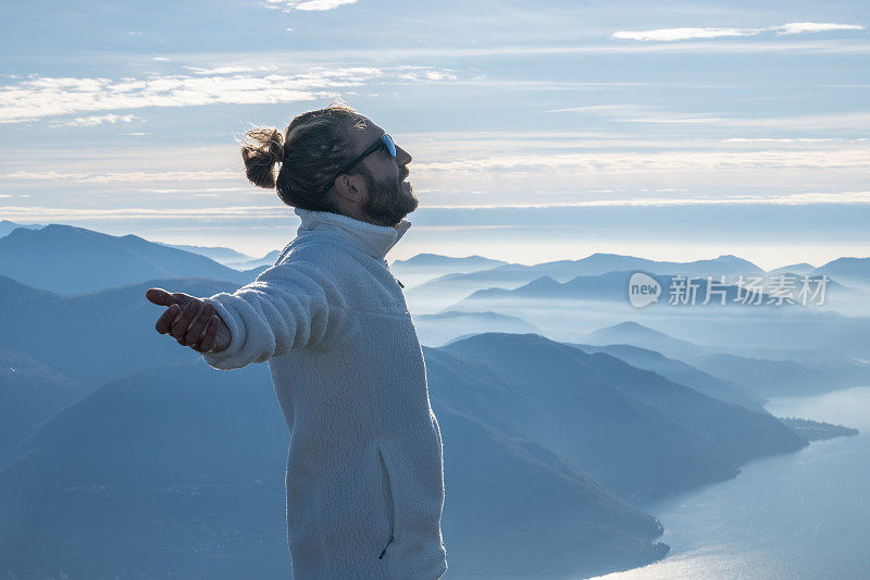 一个徒步旅行者双臂伸开站在山顶上