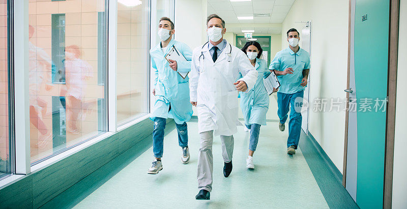 一群严肃而自信的医生戴着安全的医用口罩，在医院里为一位紧急病人快速奔跑