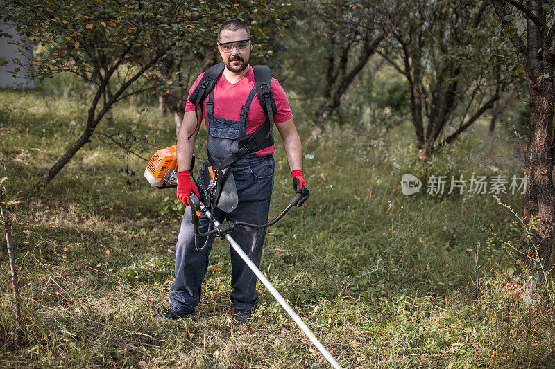 年轻的农民在自家后院割草