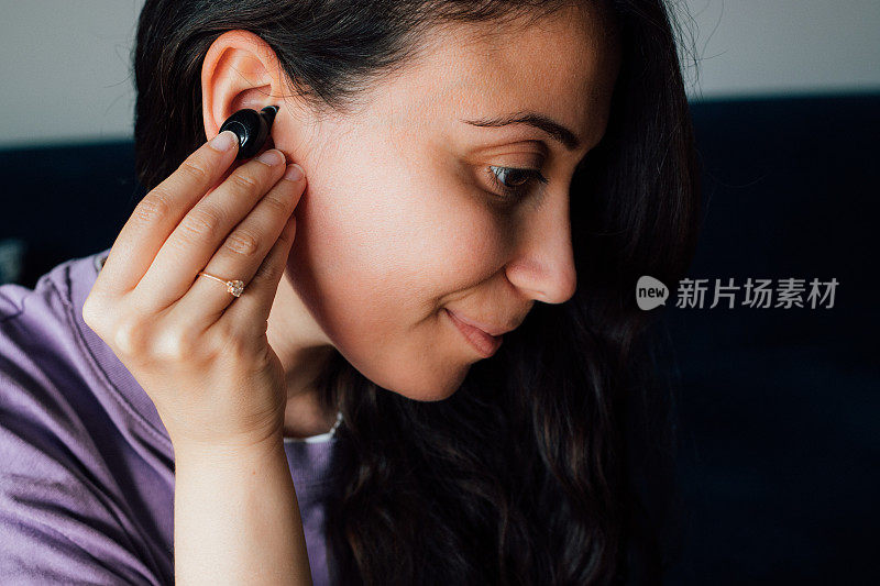 女人戴着无线耳机，拿着智能手机