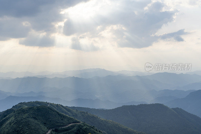 日落时透过云层和山脉的黄昏光线