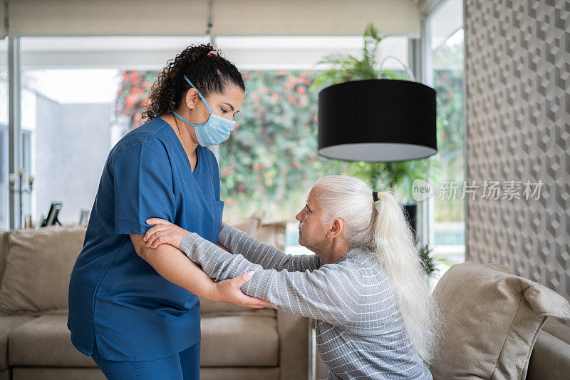 家庭护理人员帮助一位年长妇女站在家里