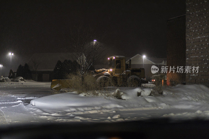 夜间暴雪前线铲雪机在停车场