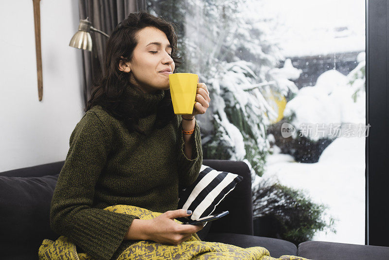 年轻女子在冬天的早晨享受着咖啡的香味