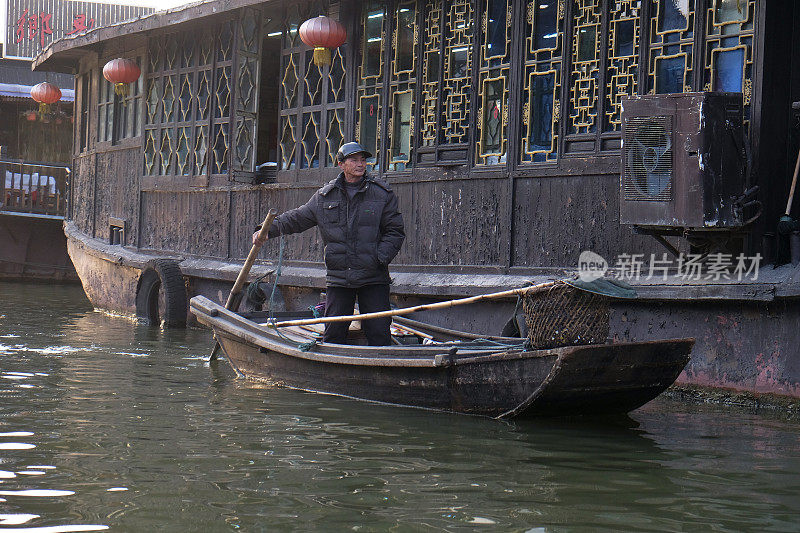在中国浙江省西塘镇的运河上，一名男子乘坐古老的木船