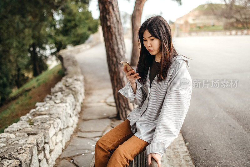 中国年轻女子在公园里玩智能手机