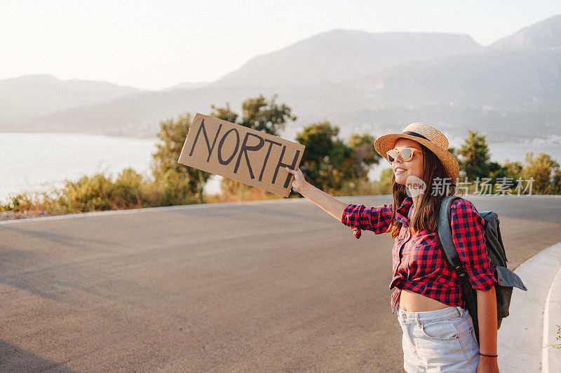 美丽的年轻女子在路上搭便车