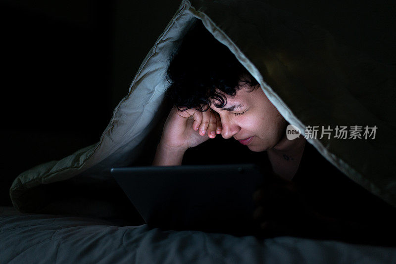 一个十几岁的女孩深夜在床上用智能手机，脸上带着睡意