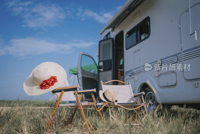 早上稻田旁停着的露营车旁，两把带草帽的露营椅