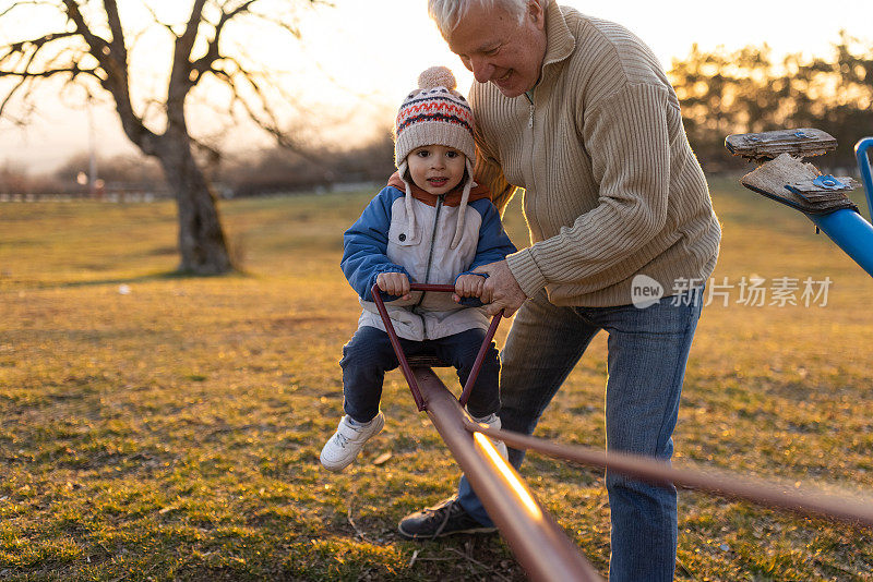 白人爷爷在跷跷板上摇孙子