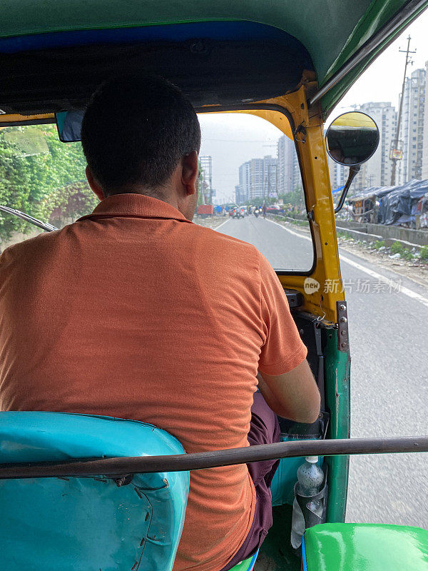 绿色和黄色人力三轮车司机在道路上行驶，后视图，聚焦前景的乘客观点的特写图像
