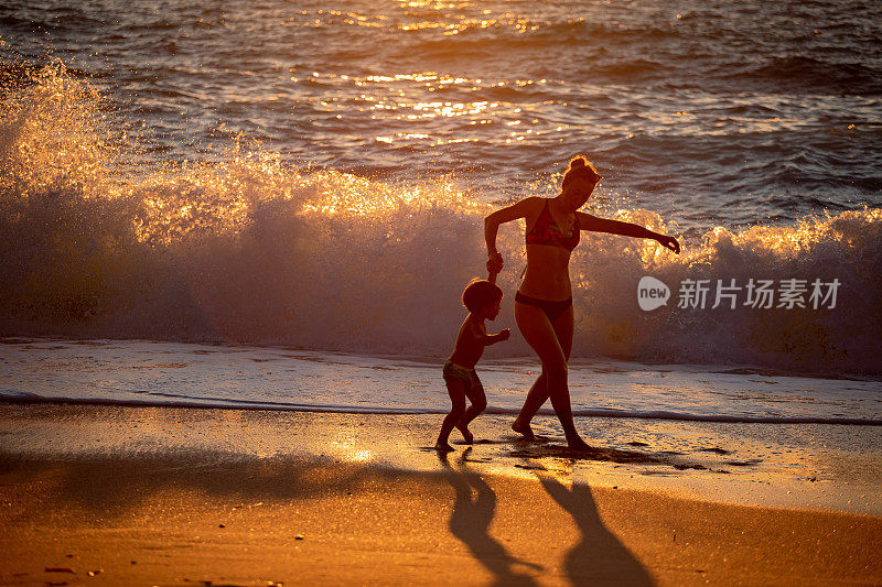 年轻的母亲和她的孩子在海滩上玩得很开心