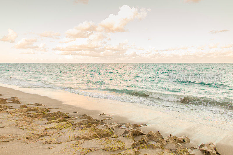2023年1月，佛罗里达州辛格岛日落时，海浪沿着空旷的岩石海滩海岸线飞溅