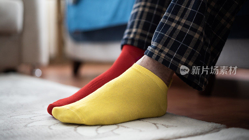 穿着睡衣，穿着红黄袜子的男人踩在地毯上
