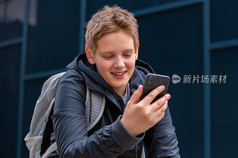 十几岁的男孩微笑着用手机和朋友视频聊天