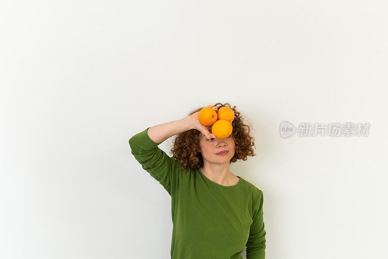 一个美丽的红发女孩拿着橙子的工作室肖像