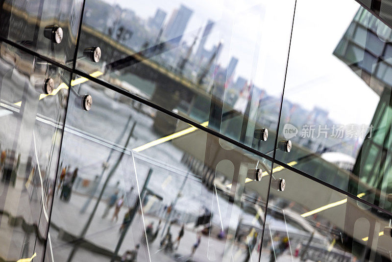 城市海港的玻璃墙反射着人们和办公楼
