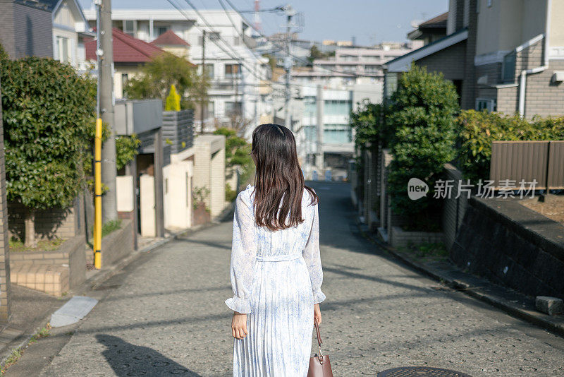 后视图的年轻女子走在居民区，回家