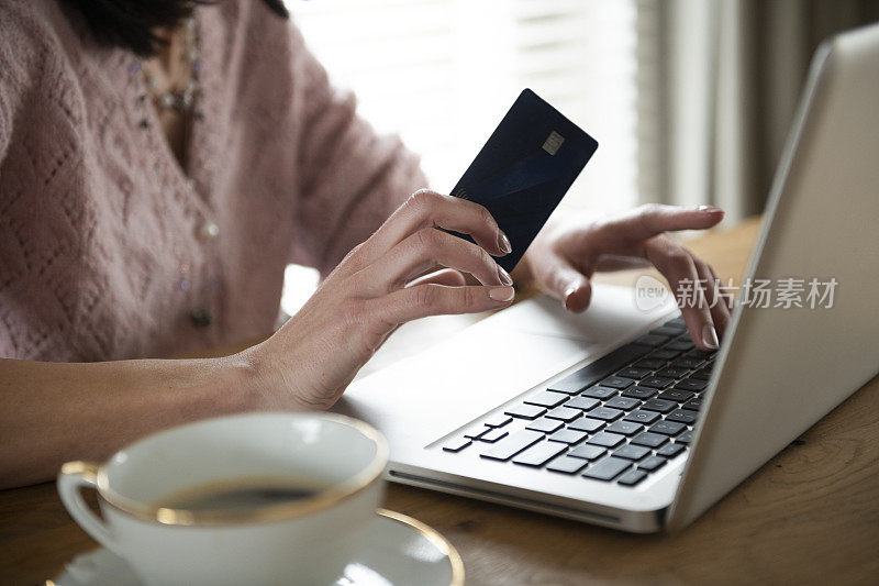 一名女子用笔记本电脑和信用卡在网上购物