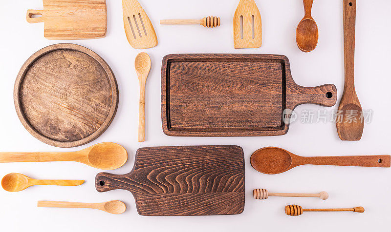 一套由环保材料制成的各种木制勺子、刮刀、砧板，放在一个轻便的台面上。厨房的背景。前视图。平躺