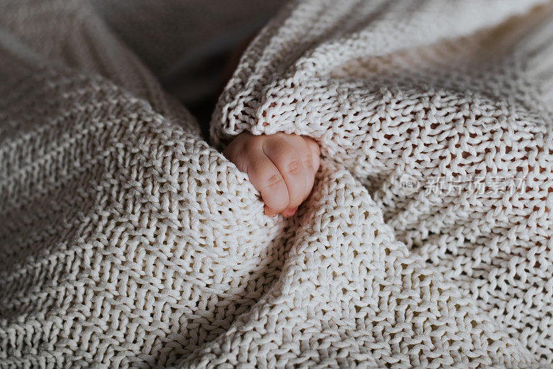 一个白种人婴儿的小手和一条针织毛毯的特写