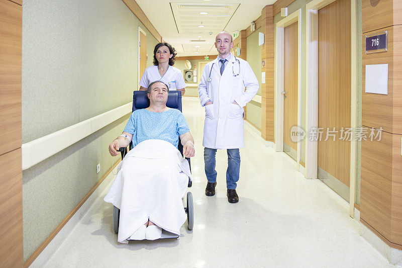 护士用轮椅抱着病人。一位女护士在医生的陪同下走在现代医院的走廊上。