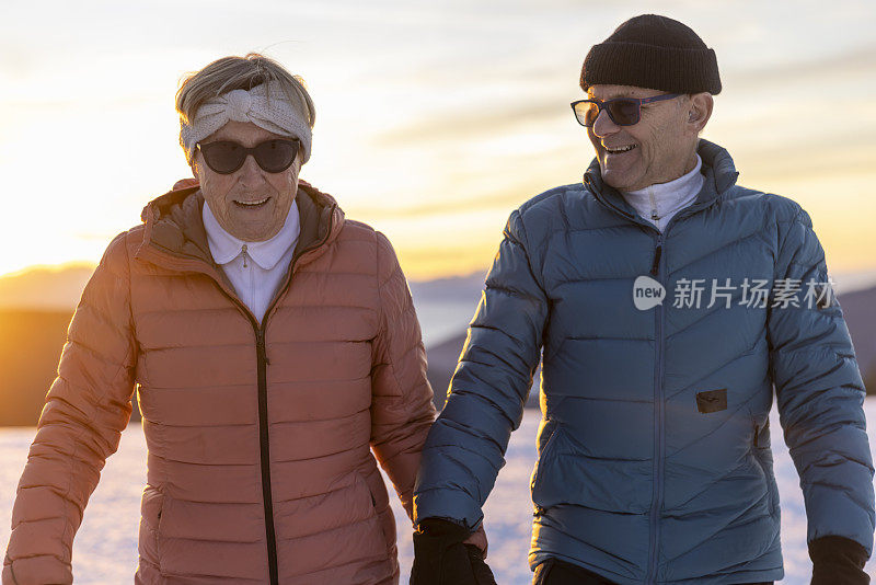 老夫妇手牵着手走在雪山上