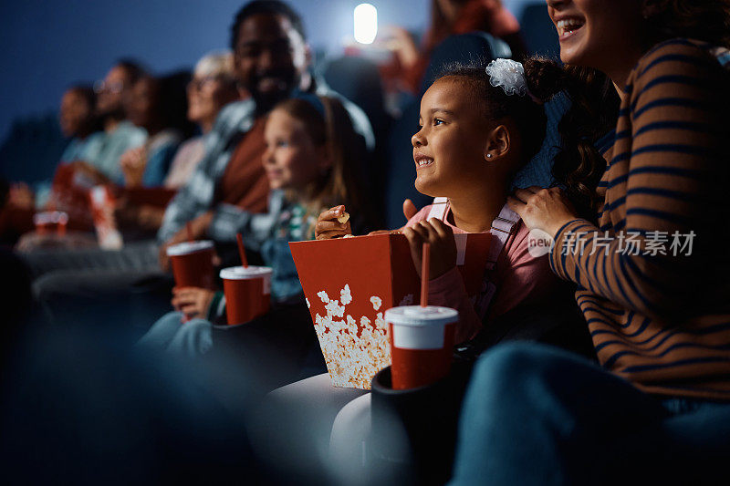 一个非裔美国女孩和她的家人在电影院看电影。