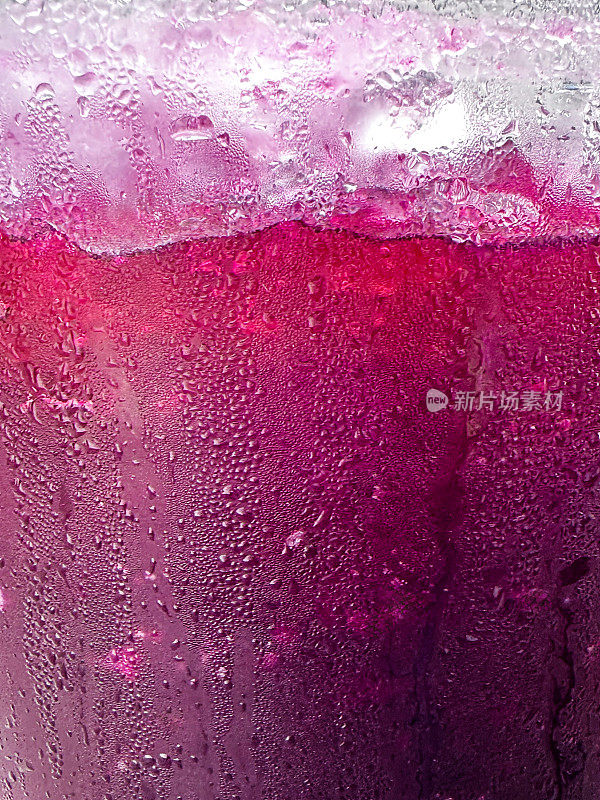全帧图像的玻璃壶覆盖了凝结与紫色饮料的黑加仑汁，冰块和碎冰泥，重点在前景