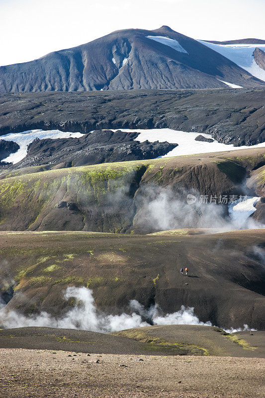 冰岛Laugevegur步道起点的Landmannalaugar周围起伏的、色彩斑斓的山脉，山谷的阴影中隐藏着积雪