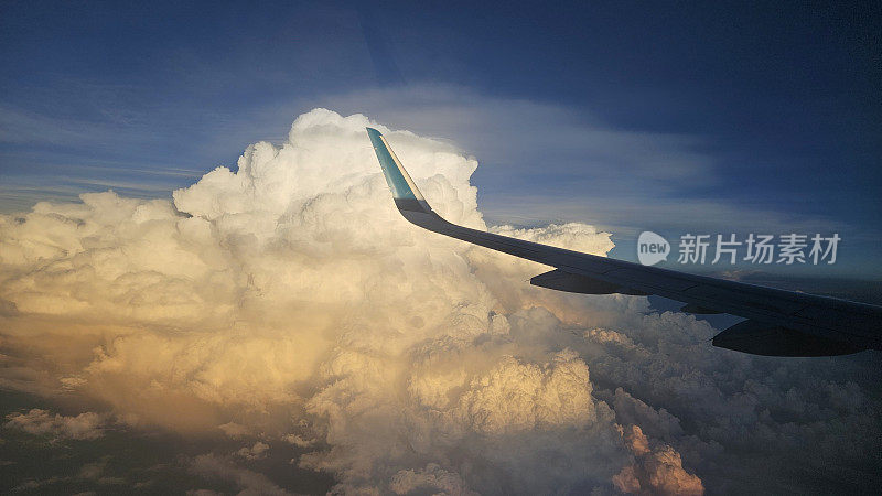 透过窗户看飞机在飞行与翅膀和蓝天云在日落。