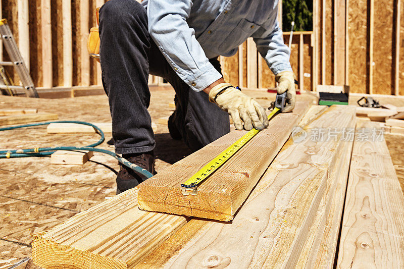建筑工人用卷尺量木梁
