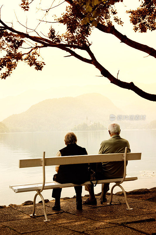一对老年夫妇坐在湖边的长椅上