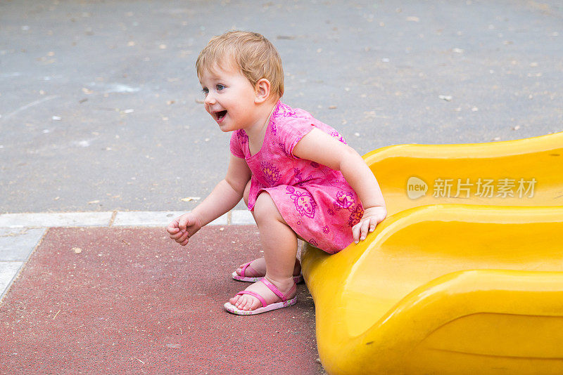 微笑的女孩在黄色滑梯游乐场