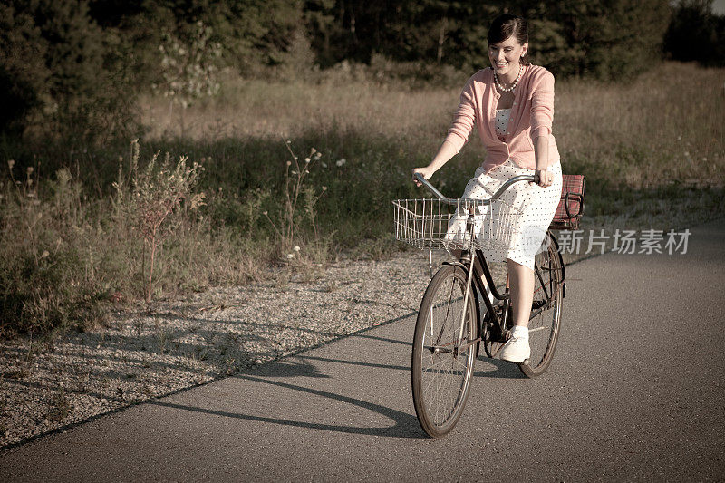 复古女孩骑着老式自行车在乡村路上