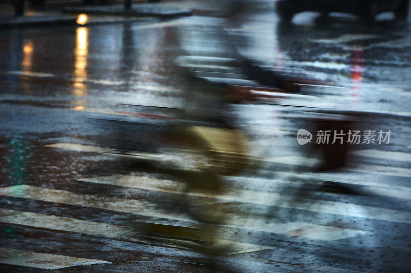 自行车在大雨中，灯光反射在潮湿的沥青上
