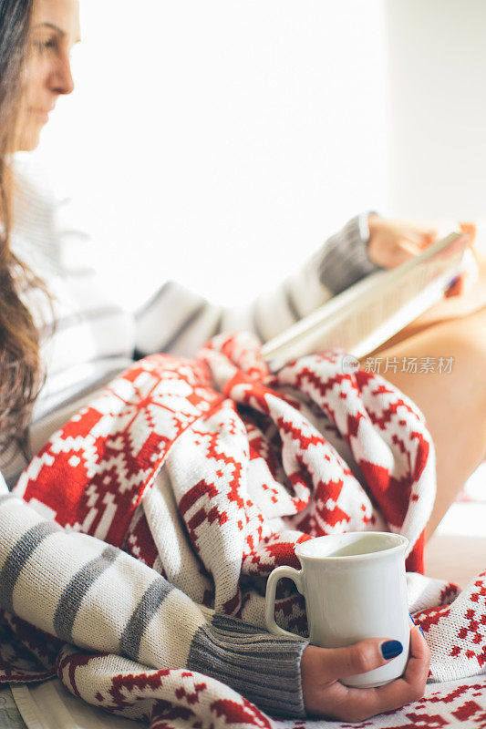 女孩在床上拿着咖啡杯看书