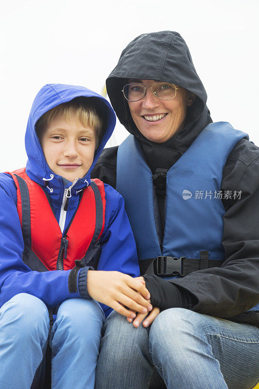母亲和儿子穿着救生衣，穿着很暖和。