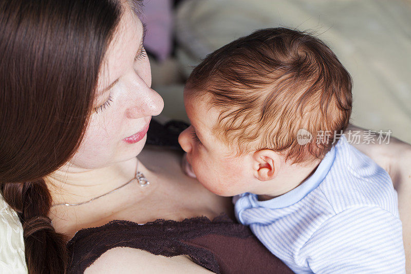 年轻的母亲和小婴儿依偎在她的胸前
