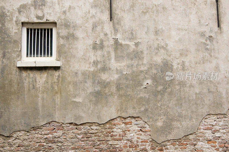 风化的监狱墙，白色的格栅窗户