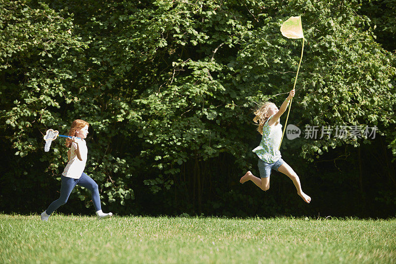 两个女孩在夏日的田野里追逐蝴蝶