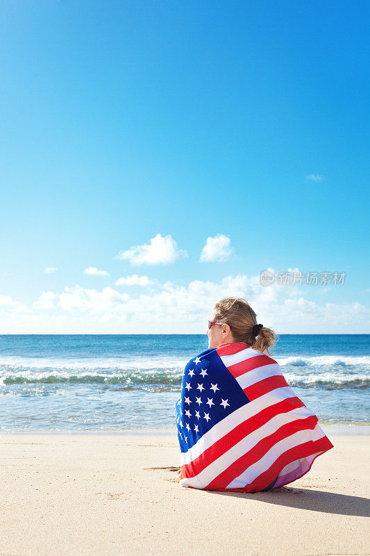 美国国旗毛巾包裹的女人度假在热带夏威夷海滩