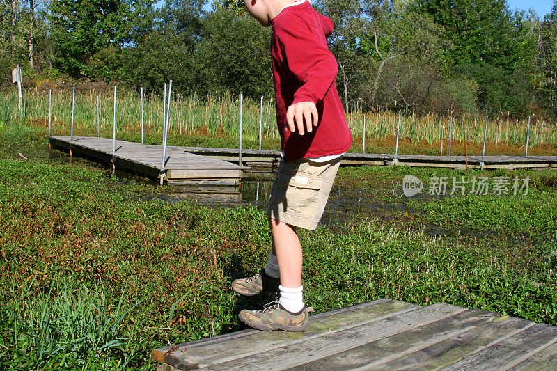 泥巴的跳跃:男孩从船坞走到沼泽里