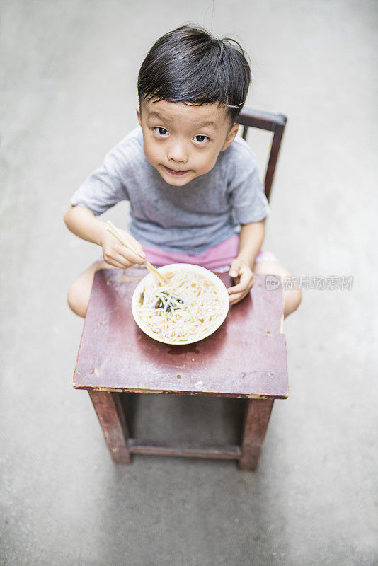 快乐的亚洲孩子用筷子吃美味的面条