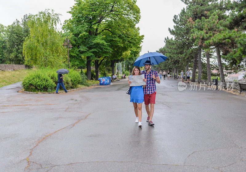 一对年轻的游客在雨天在城市里寻找乐趣