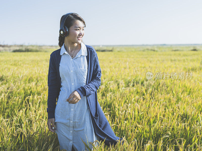 年轻女孩戴着耳机在野外