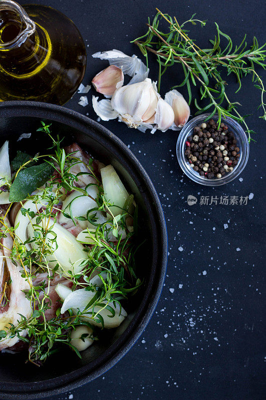 生牛肉与新鲜的香草在铸铁煎锅黑色背景